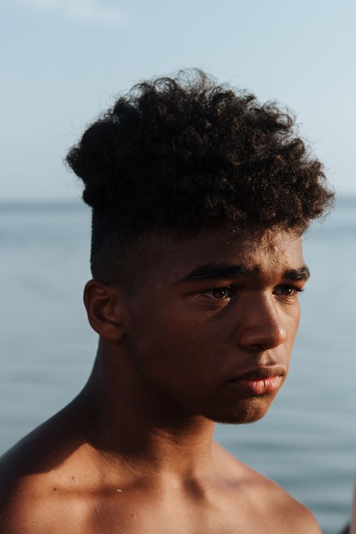 Free Close-up portrait of a thoughtful teenager with curly hair by the sea, captured during a summer vacation. Stock Photo