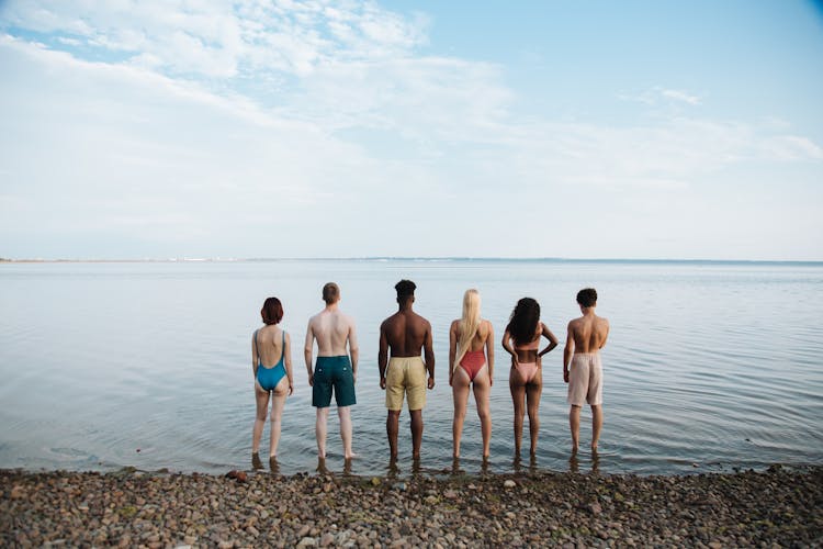 Rear View Of Teenagers Standing On Beach