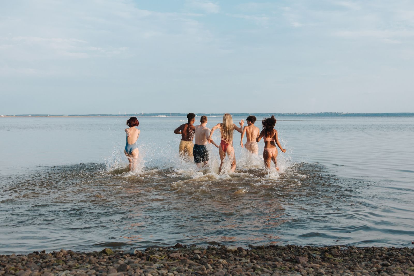 A group walking into the ocean together, laughing.
