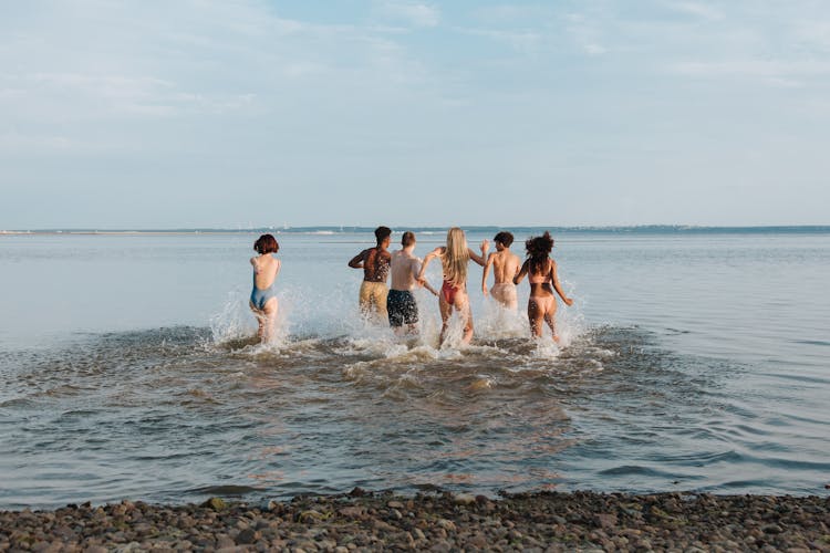 Rear View Of Friends Running In Sea