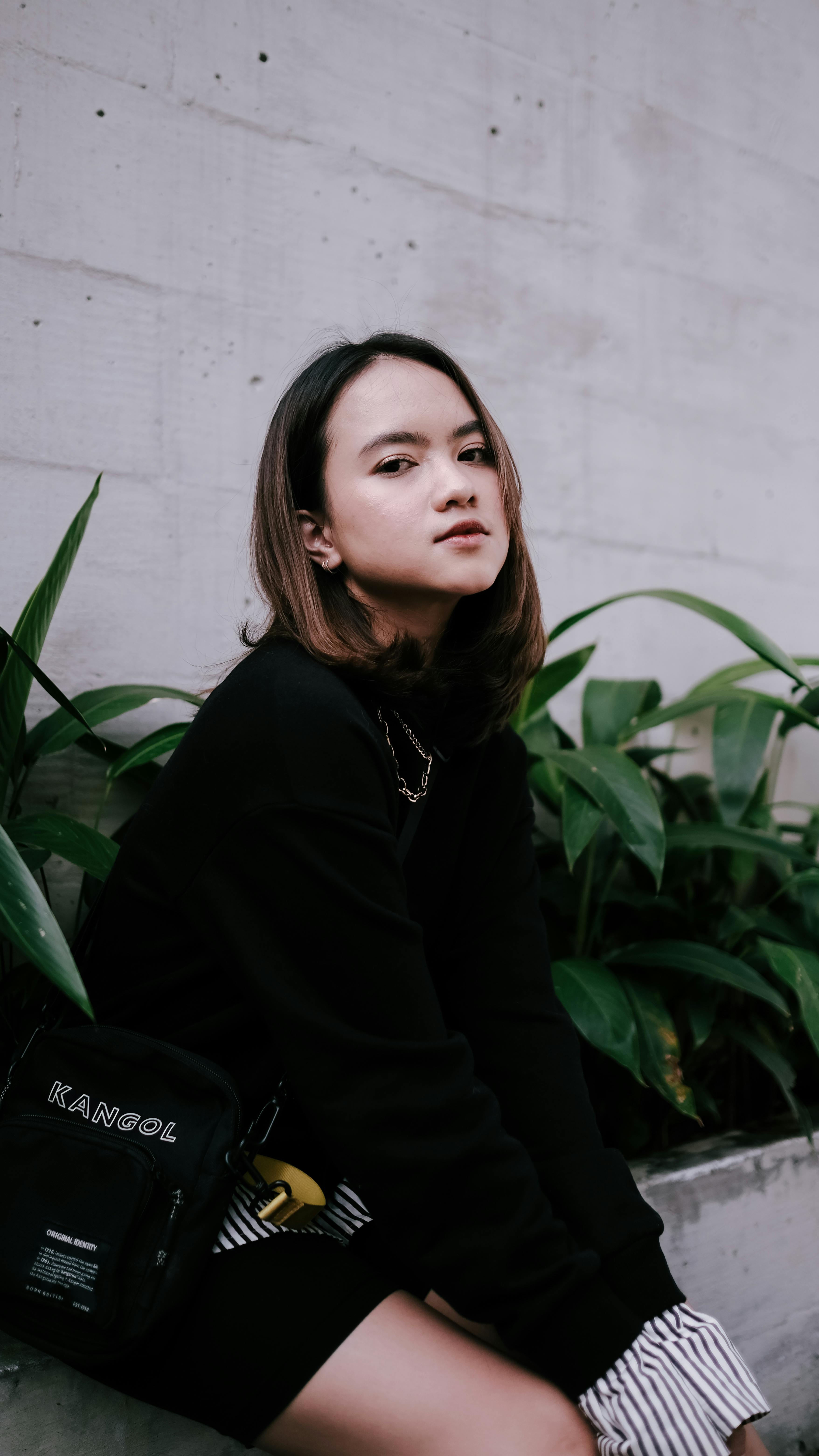 Stylish woman in streetwear sitting outdoors with a trendy look.