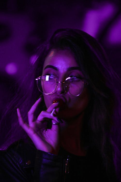 A Woman Wearing Eyeglasses Eating Lollipop