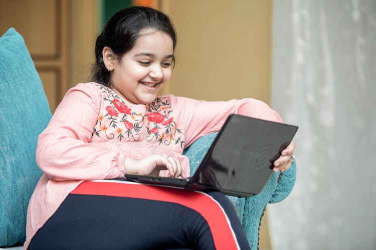 A Smiling Girl Using A Laptop