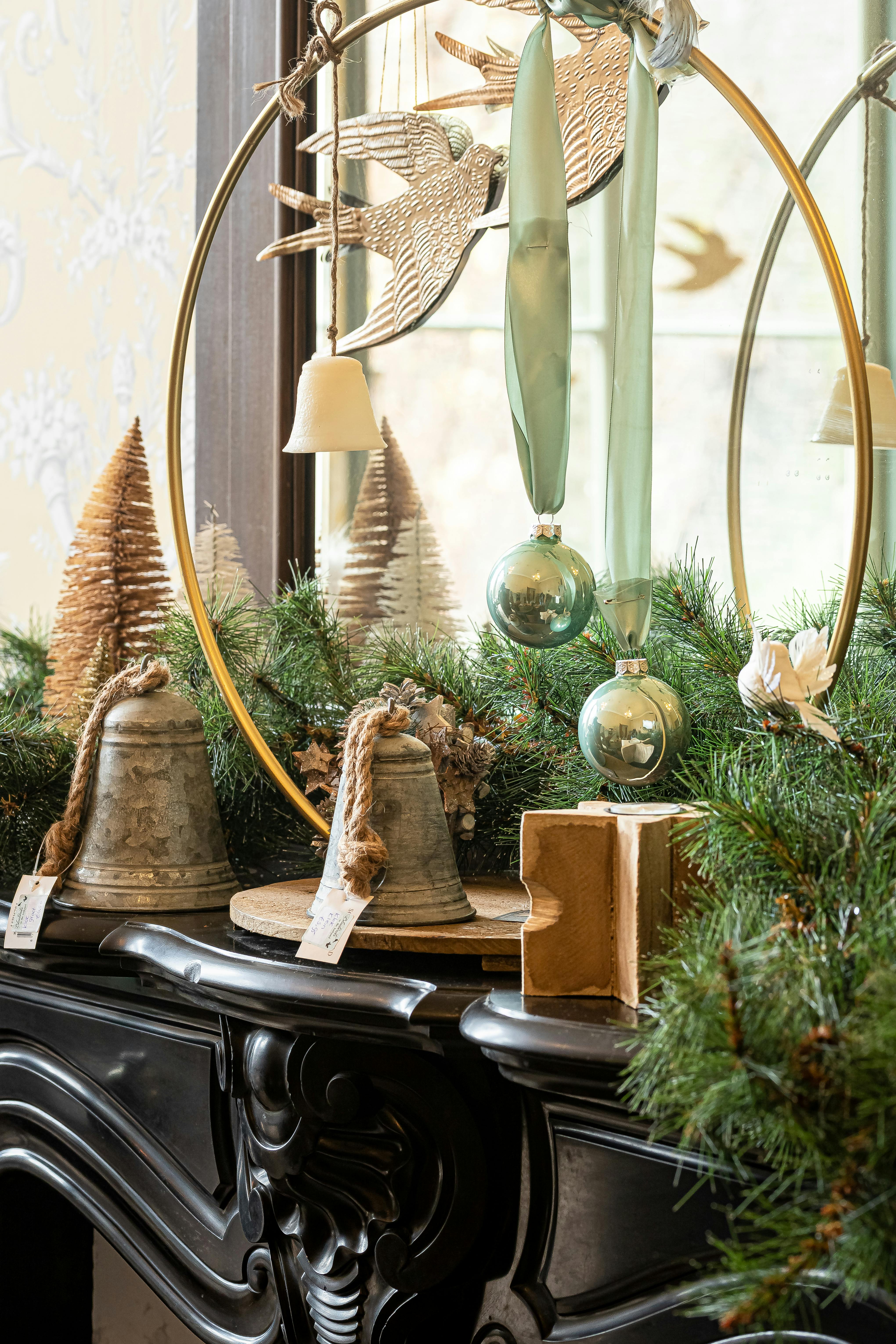 Stylish Christmas decorations with bells and ornaments on a mantelpiece.