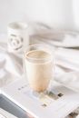 Big Cup of Milky Coffee Standing on Books Laying by Bed