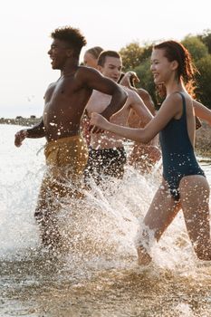 A group of diverse teenagers enjoying a fun summer day by the seaside, splashing through the water.