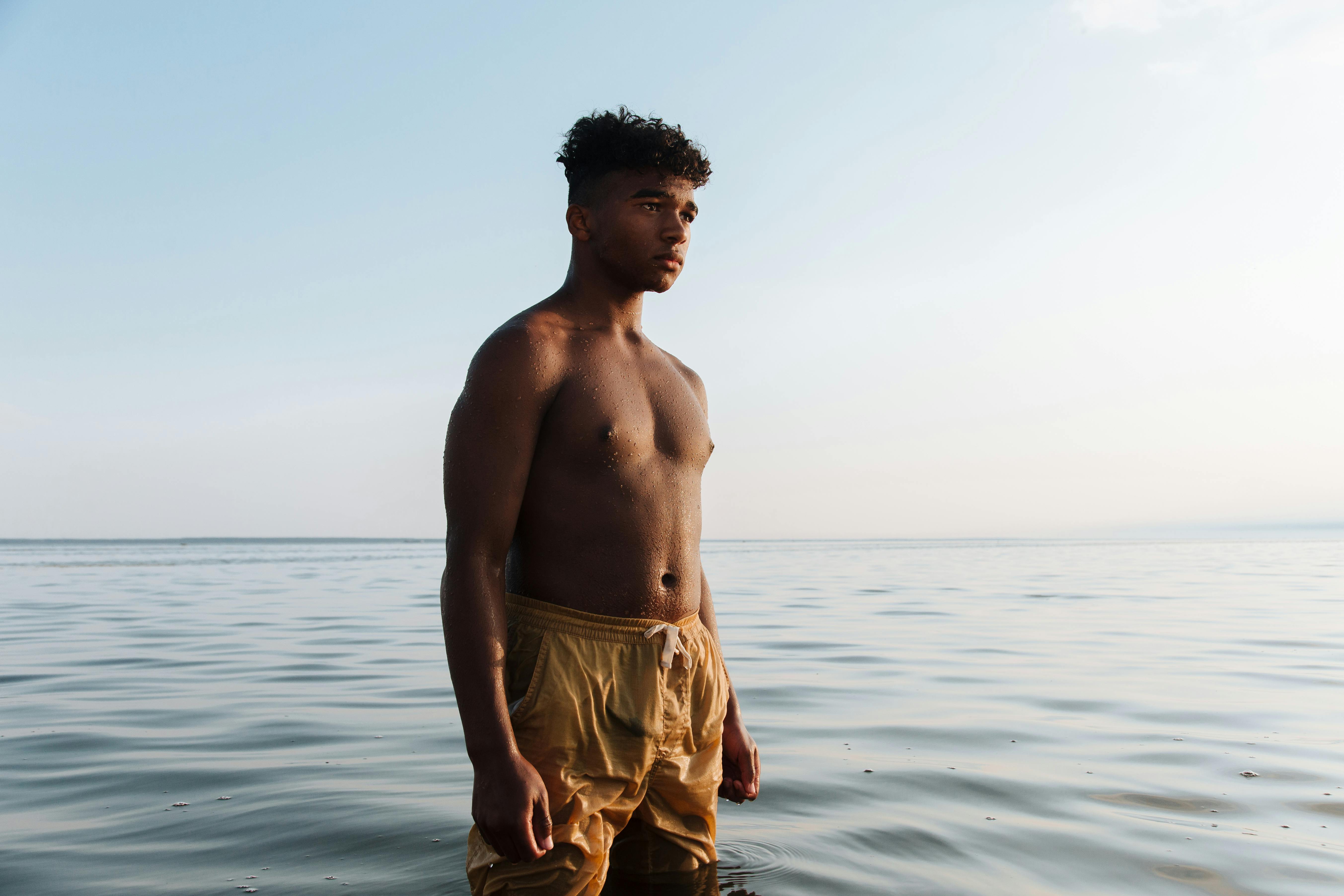 Portrait of Shirtless Teenage Boy Standing in Water · Free Stock Photo