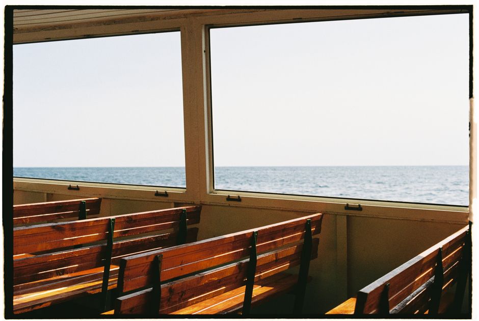 Capture the calm of the ocean from a wooden bench on a ferry, offering a tranquil sea view.