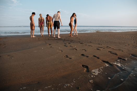 Diverse Group of People in Swimwear Looking for Something in Sandy Beach