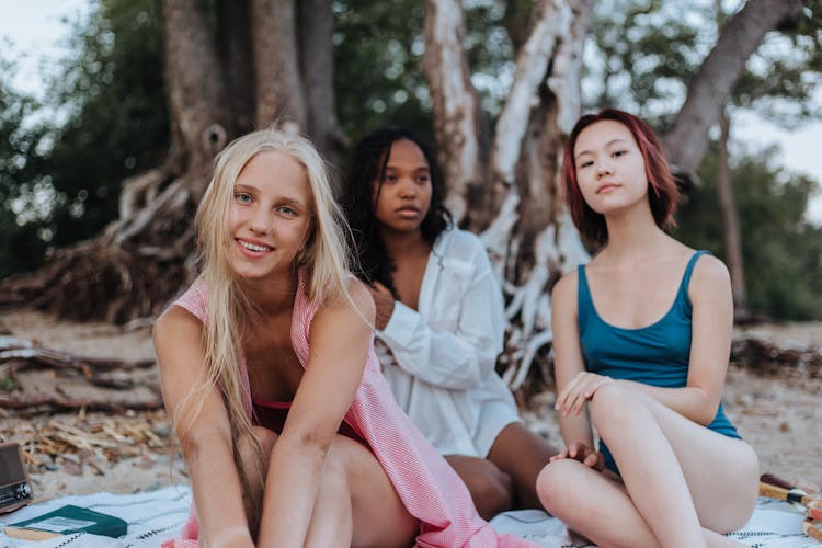 Girls Sitting On A Blanket On The Beach