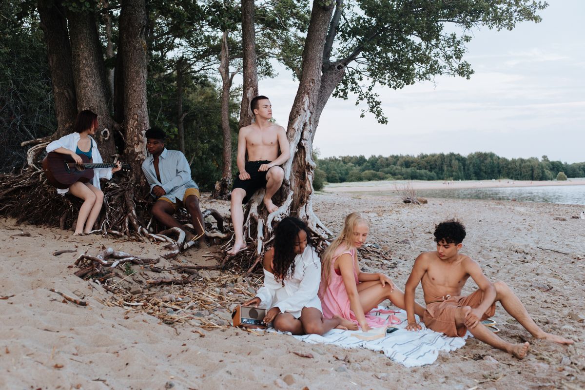 A diverse group of teenagers enjoying a seaside picnic together