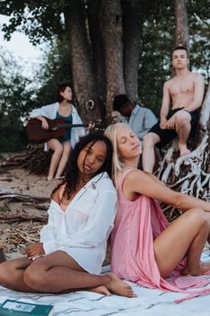 A group of teenagers enjoying a summer beach picnic with music and relaxation.