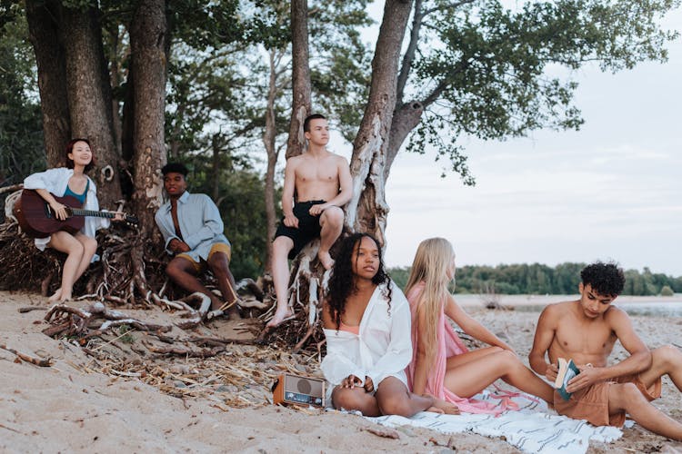 Teenage Friends Relaxing On The Beach By The Sea