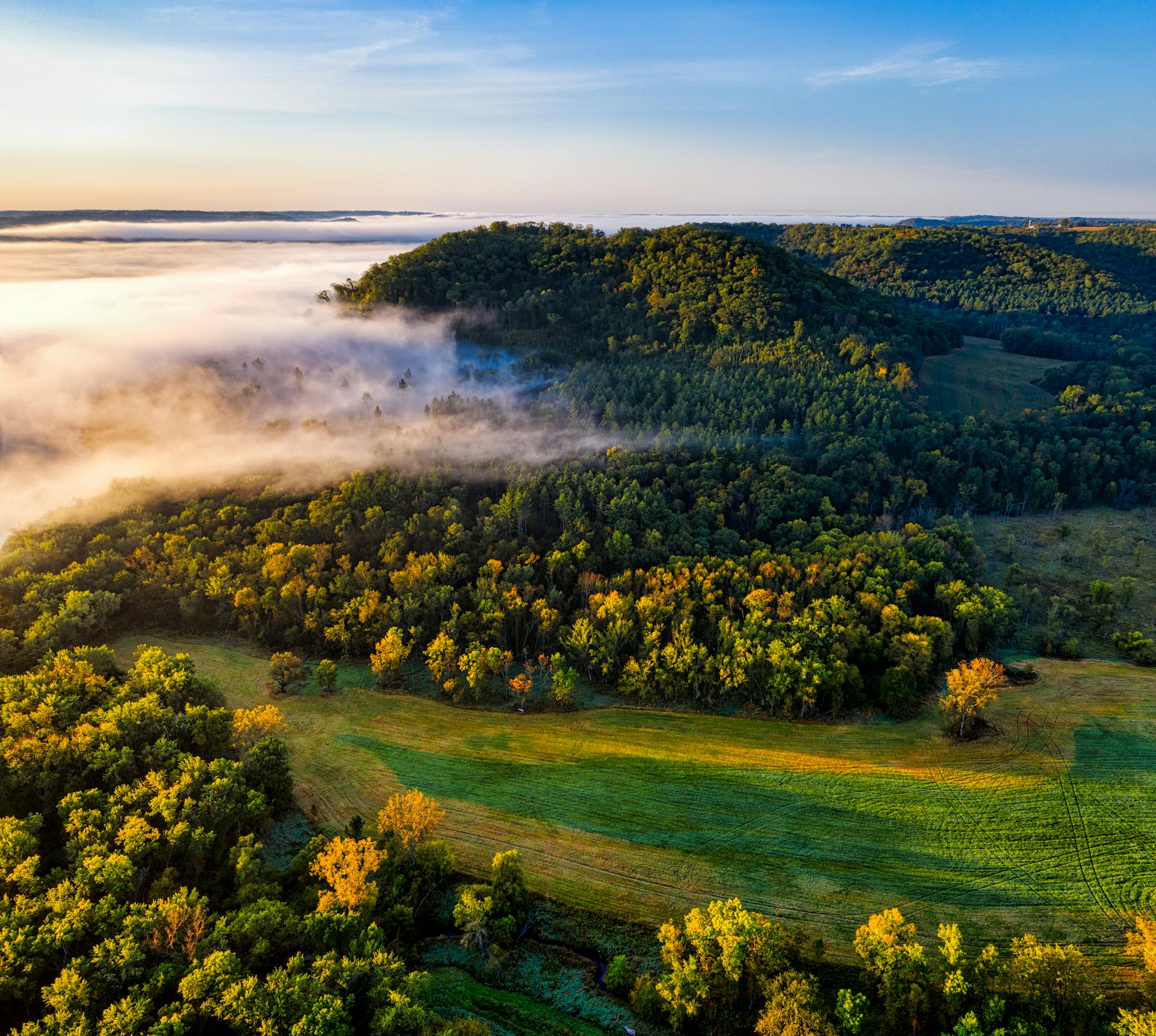 A breathtaking aerial view of a misty forest landscape in Ella, Wisconsin during sunrise.