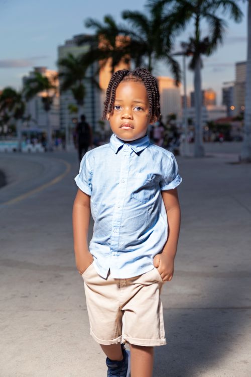 Free A young boy with braided hair in a stylish outfit standing outdoors in Angola. Stock Photo