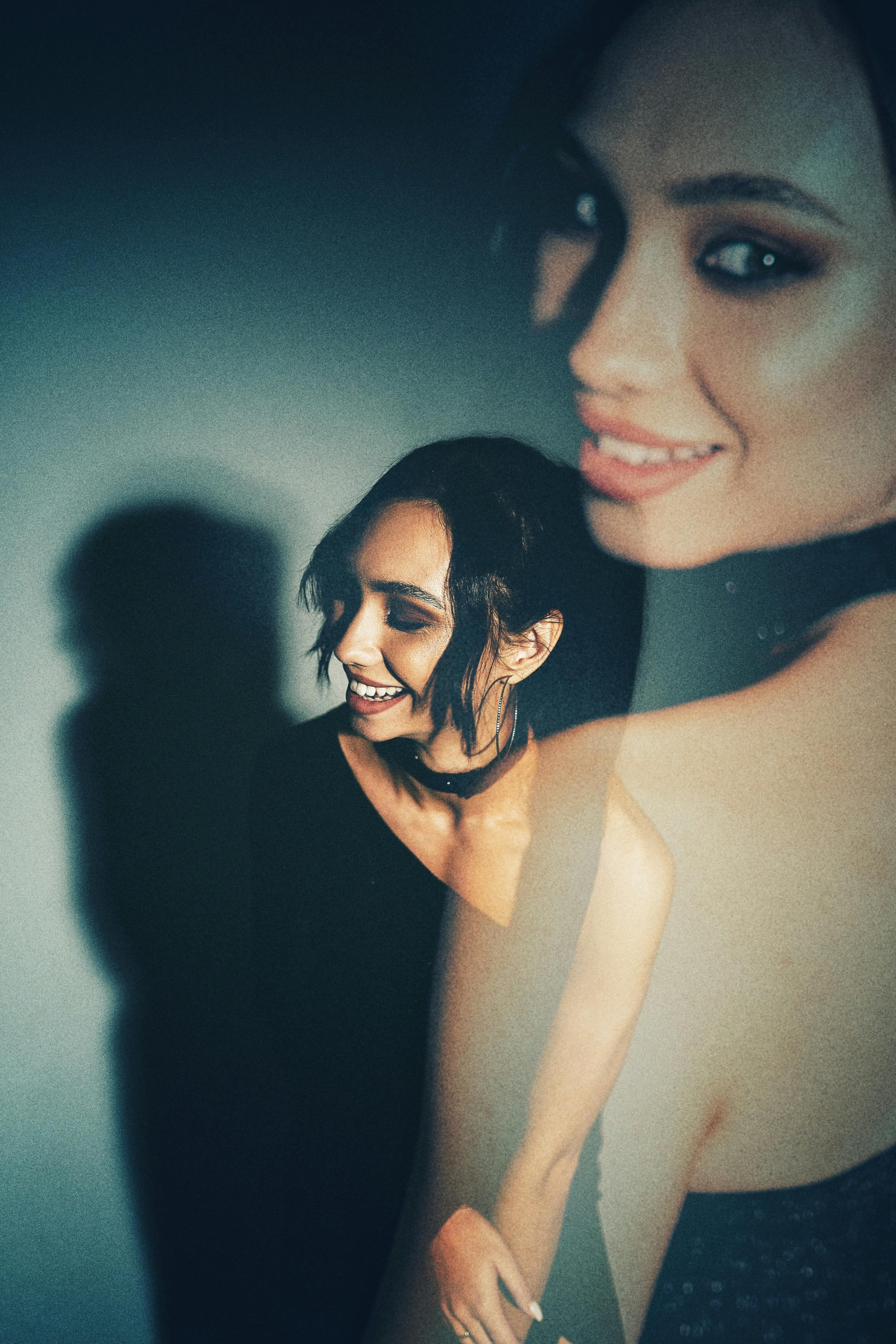 Creative portrait featuring a smiling woman in a dark, artistic double exposure effect.