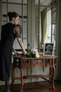 Woman in Black Dress Standing Beside Brown Wooden Table