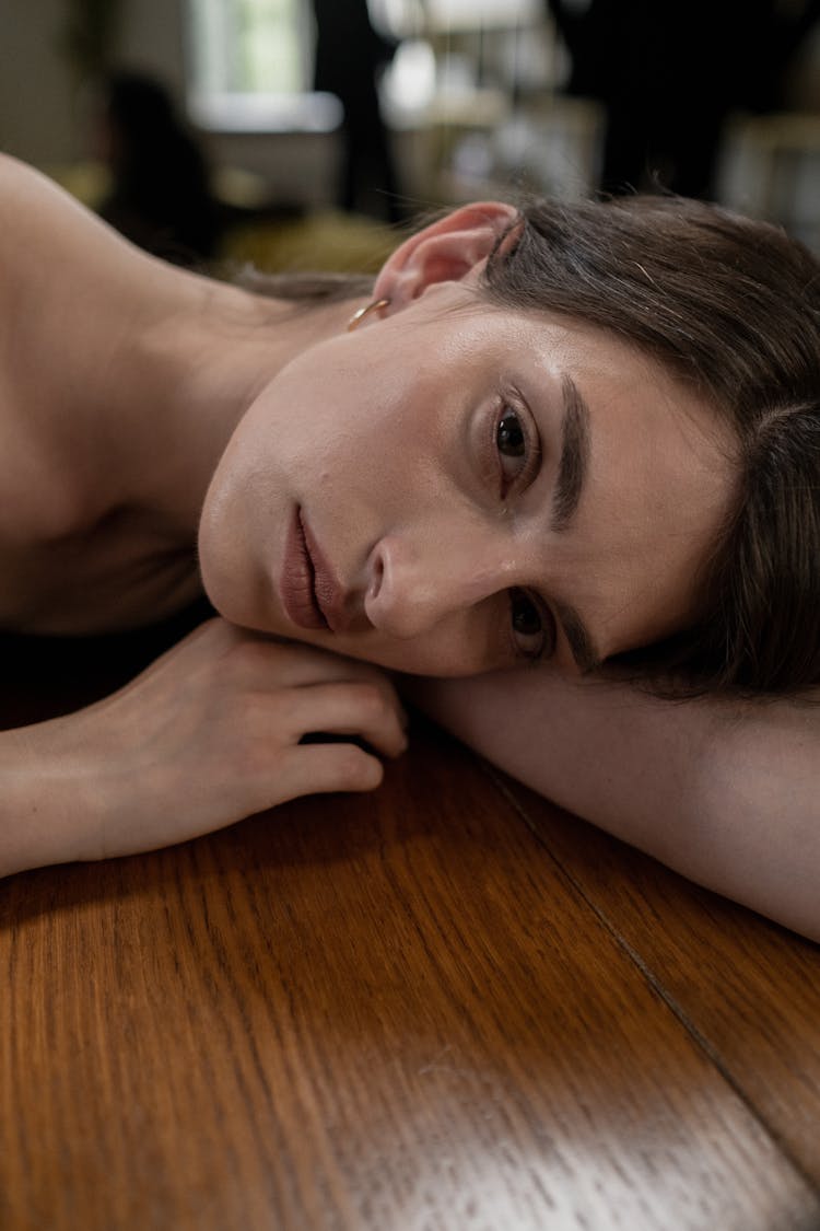 A Woman Leaning On A Wooden Table