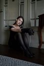 A Woman in a Black Off-Shoulder Dress and Gloves Sitting on the Floor