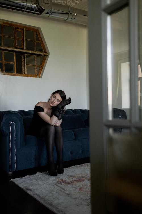 Woman in Black Dress Sitting on Blue Couch