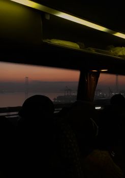 Silhouette view of Istanbul's Bosphorus and cityscape at dusk from a bus window.