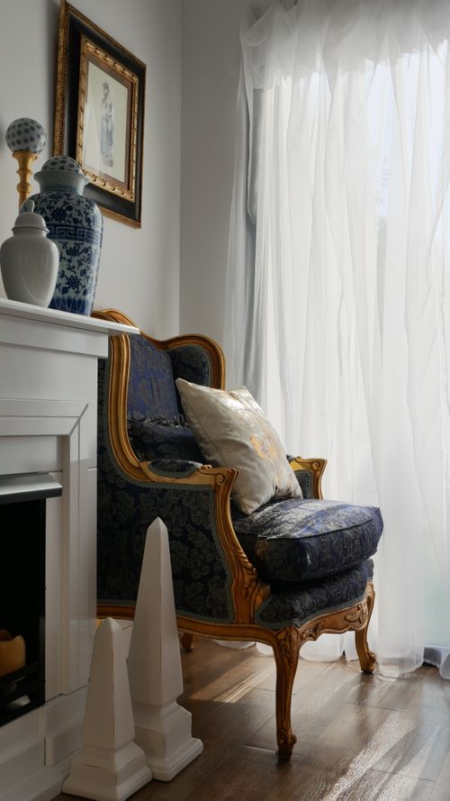 Free A stylish room interior featuring a classic armchair, vases, and curtains by a bright window. Stock Photo