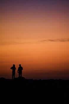 A captivating silhouette of two people standing against a vibrant sunset sky.