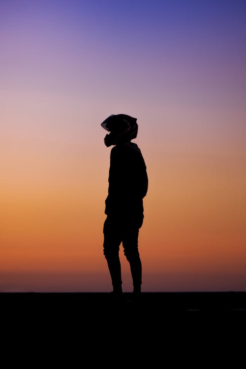 Silhouette of Man Wearing Helmet during Sunset