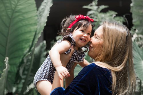 Free Mother and baby share a heartwarming moment in nature with bright sunlight and greenery. Stock Photo