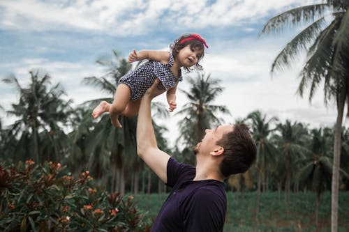 Man Lifting Up a Baby Near Trees 