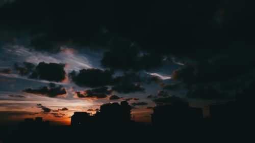 Free Silhouetted buildings against a vibrant evening sky with dramatic clouds. Stock Photo