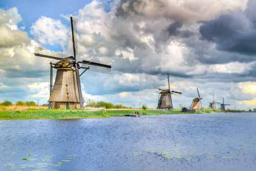 Free Picturesque view of historic Dutch windmills on a cloudy day by the water. Stock Photo