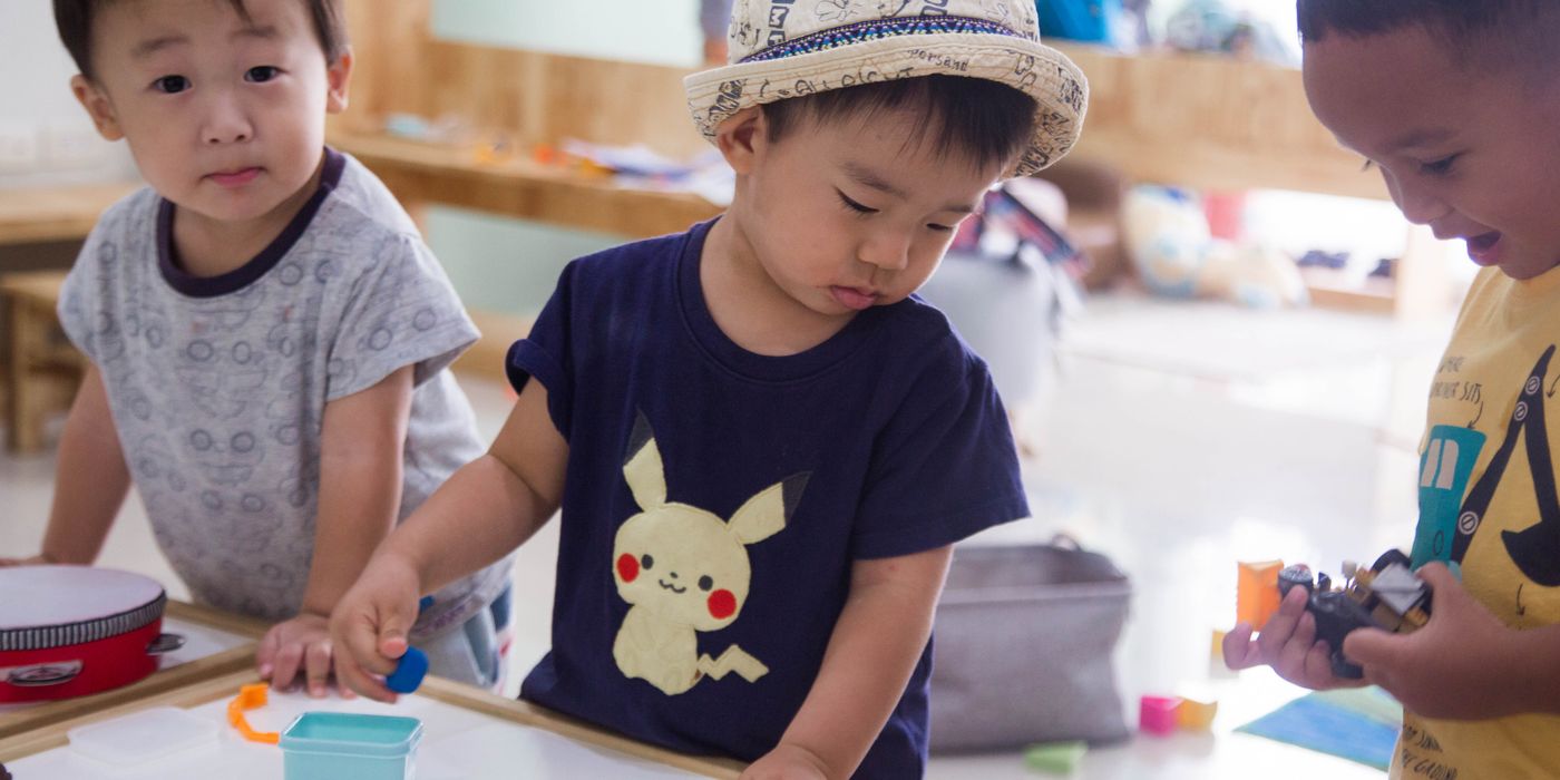 Three young children playing creatively indoors with toys and art supplies.