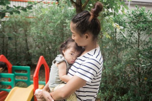 Free A woman holds a baby in an outdoor garden, conveying warmth and care. Stock Photo
