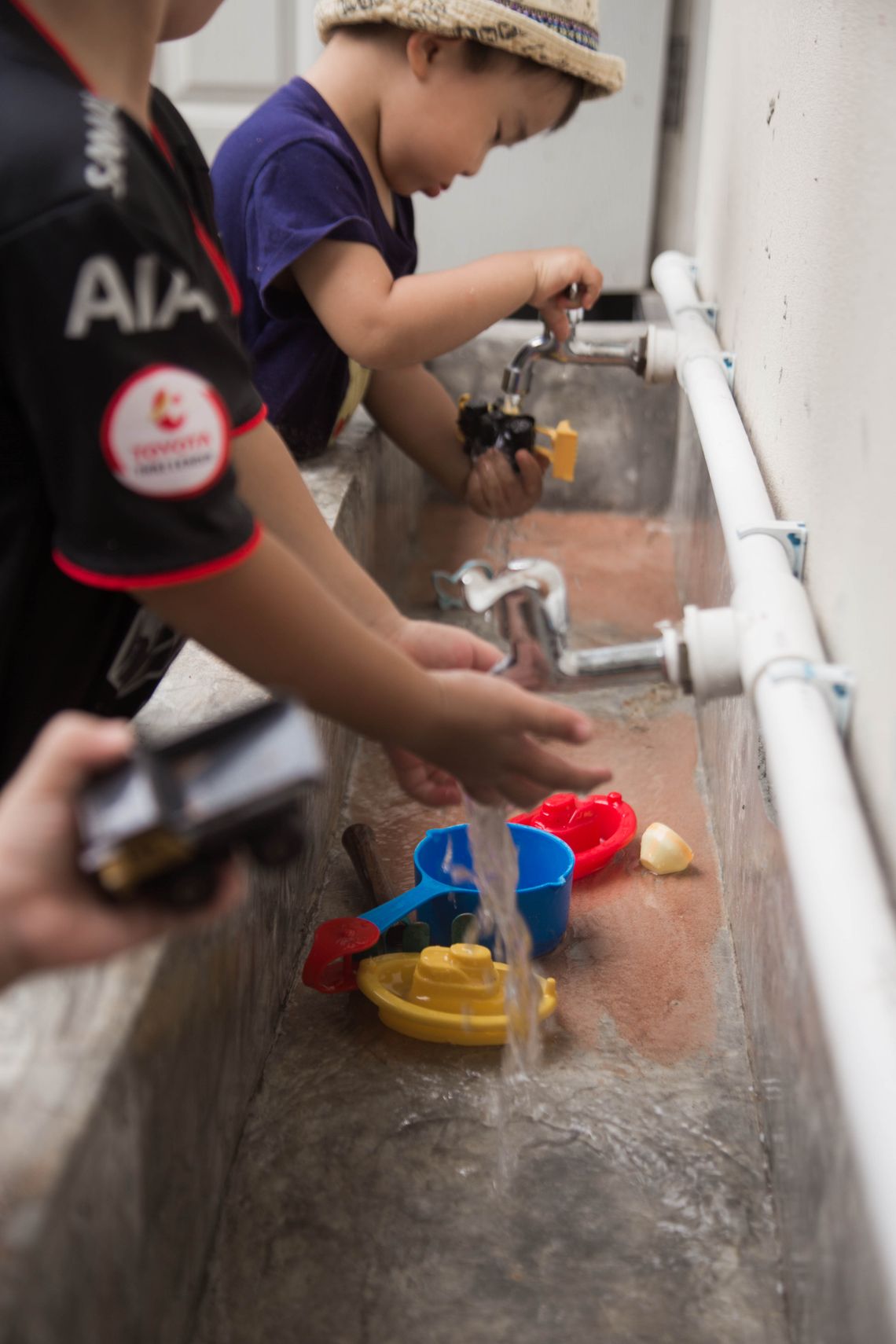 Children washing colorful toys together outdoors