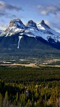 Breathtaking winter view of Three Sisters peaks in Canmore, Alberta against a clear sky.
