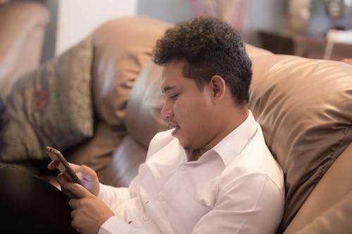 A Man Sitting on the Couch Browsing His Smartphone
