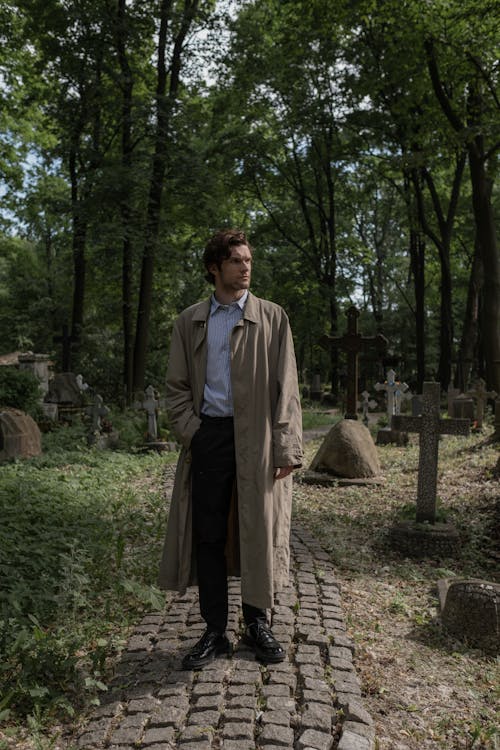 A Man in a Trench Coat Standing in a Graveyard