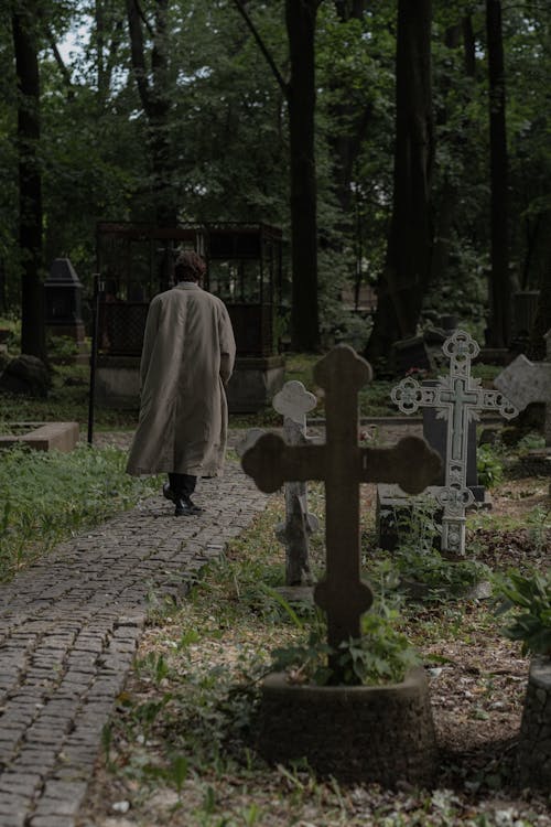 Free Back View of a Man Walking in a Pathway in a Cemetery Stock Photo