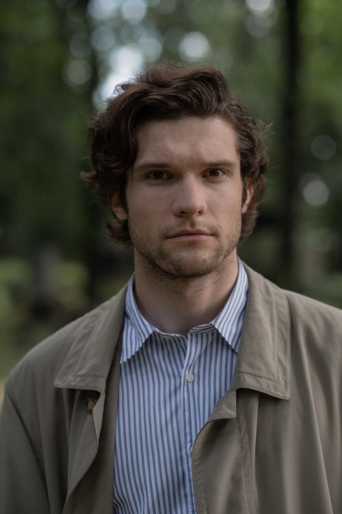 Free A thoughtful young man with messy hair in a trench coat standing outdoors. Stock Photo
