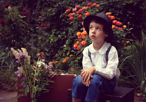 一个戴着帽子的小孩坐在鲜艳的花丛中，显得纯真而富有想象力