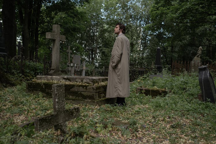 Man In Long Coat Standing In A Cemetery 