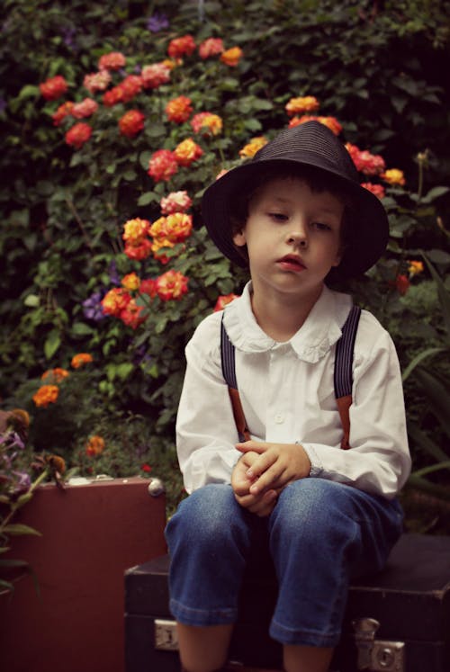 戴黑帽子的男孩坐在花附近的案件