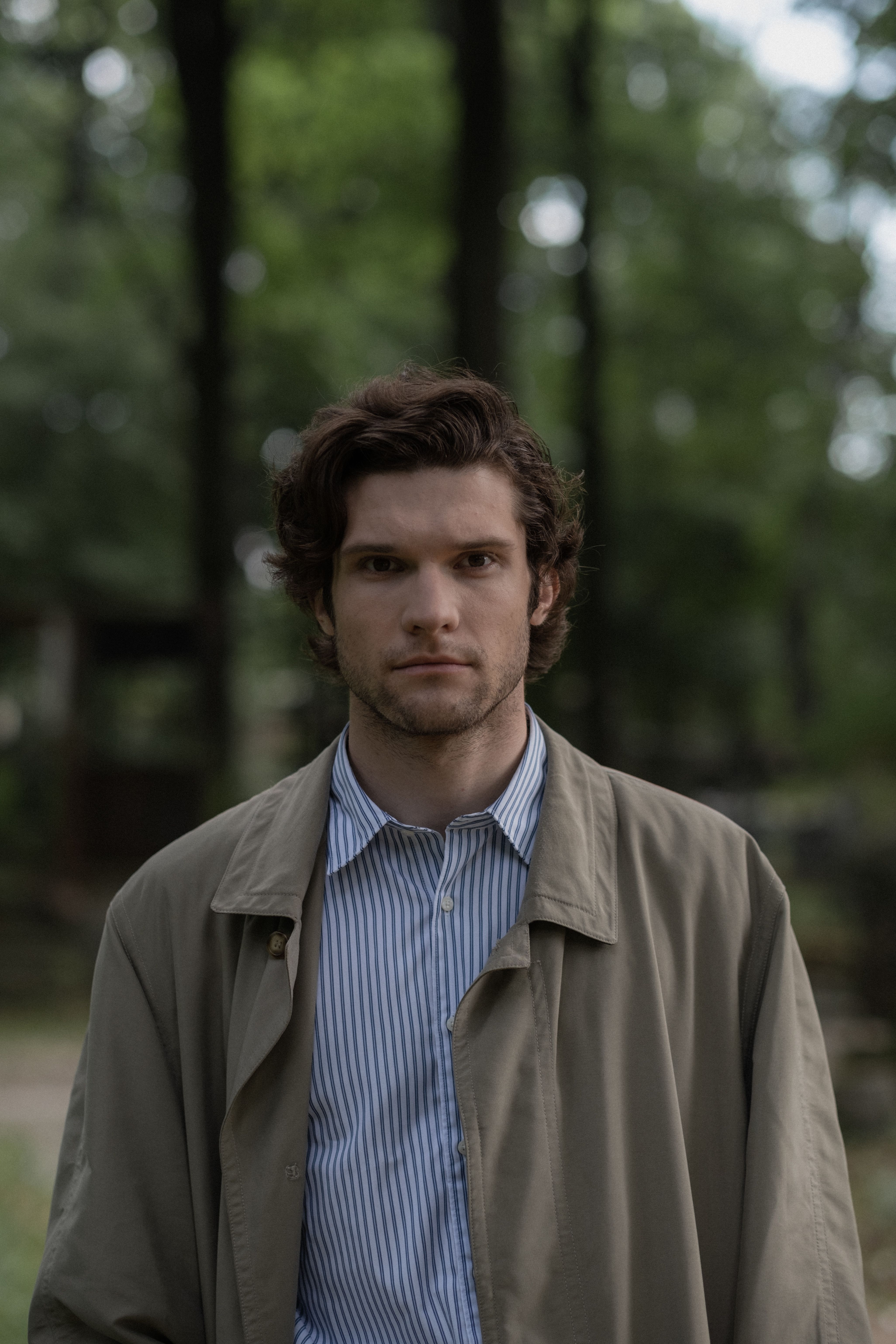 Casual portrait of a man outdoors with blurred forest background.