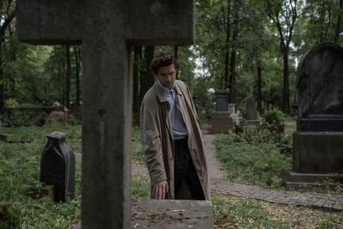 Free Caucasian man in trench coat mourns at a rustic cemetery during the day. Stock Photo