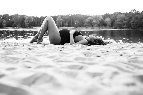 A Pregnant Woman in a Bathing Suit Lying on the Sand
