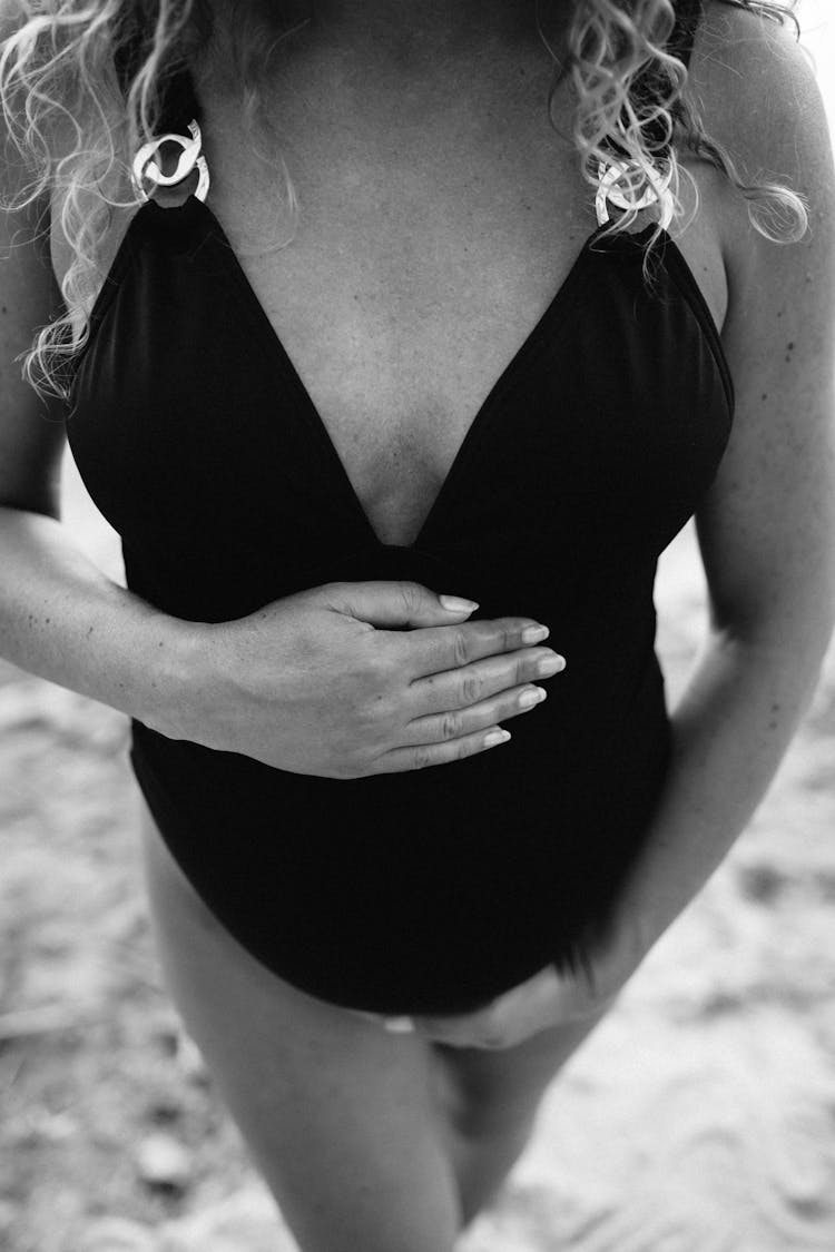 A Pregnant Woman In A Bathing Suit Holding Her Tummy