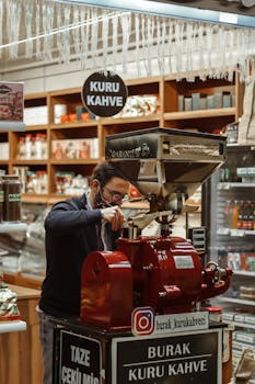 Man using traditional coffee grinder in Turkish coffee shop, surrounded by products.