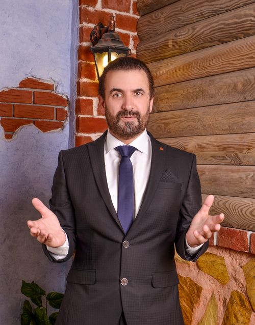 Free Confident businessman in a suit poses outdoors against a rustic wall. Stock Photo