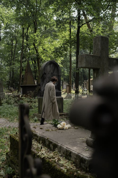 Free A Man in a Trench Coat Walking at a Cemetery Stock Photo